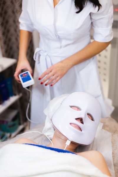 the client lies in the salon on the cosmetology table with a white mask on her face